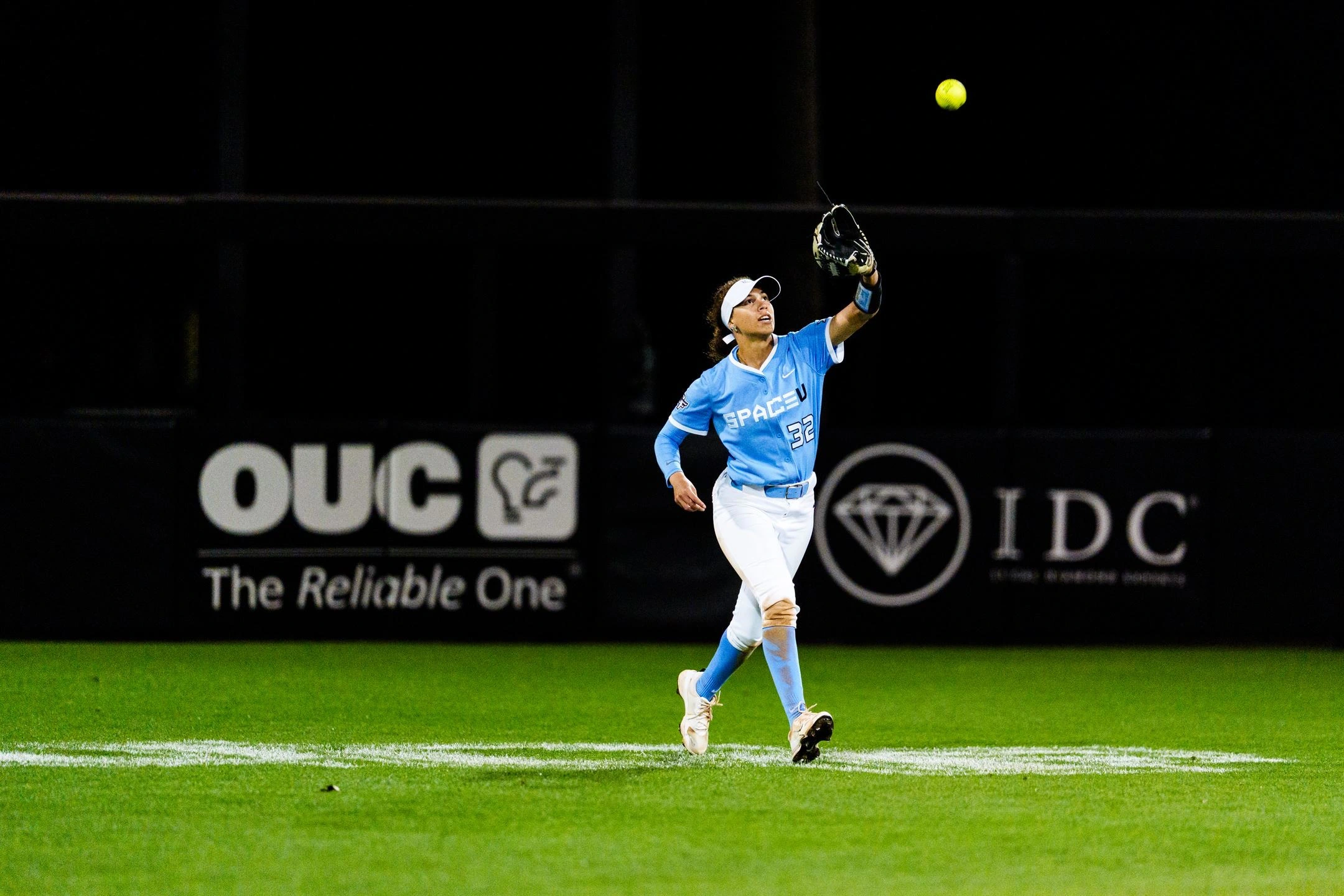Zoe Calvez tracking a fly ball in the outfield during a night game
