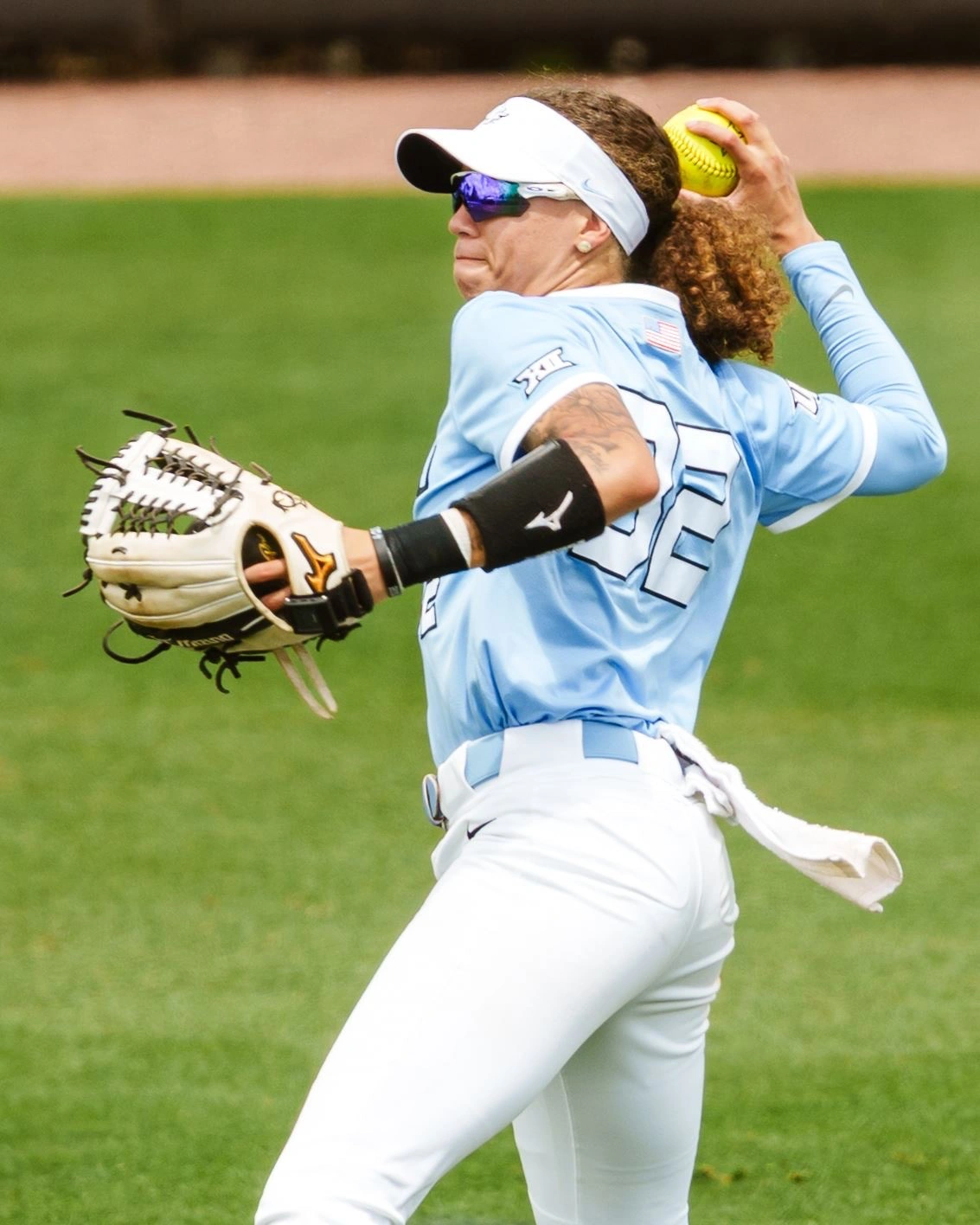 Zoe Calvez in UCF's light blue alternate jersey, stepping into a throw from the infield